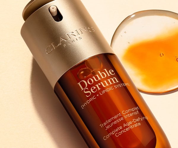 Butelka serum Double Serum z rozpylaczem i otwartym słoiczkiem z przezroczystym żelem na beżowym tle.