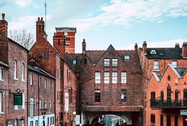 Red brick Victorian buildings and a clock tower in a historic town street lined with period architecture