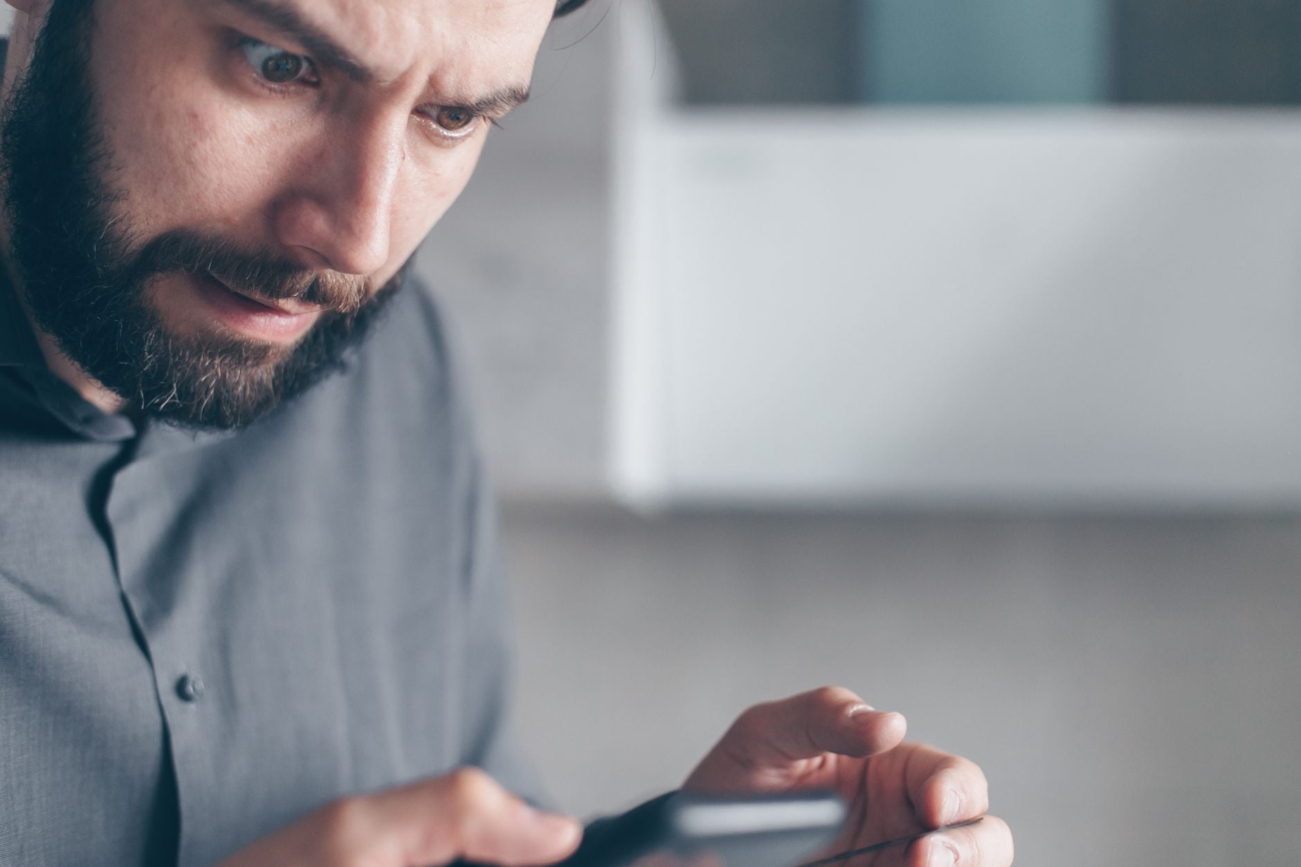 Mężczyzna patrzący na ekran tabletu z zainteresowaniem i skupieniem.